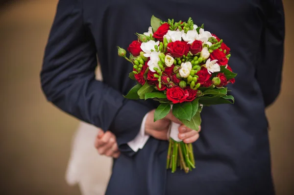 Elegante novia y novio sosteniendo ramo detrás de su espalda — Foto de Stock