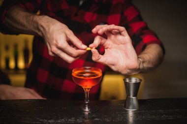 Barmen bir kokteyl cam içine portakal kabuğu sıkma