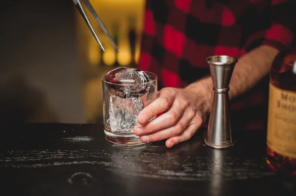 Barman vertiendo hielo en vidrio. Barman preparando bebida de cóctel. . — Foto de Stock