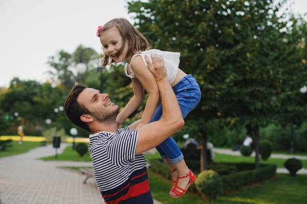 Happy family Dad throws child daughter up on a walk  in park — Stock Photo, Image
