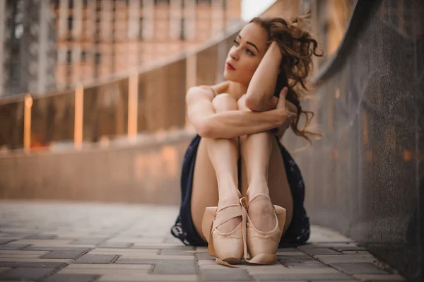 Jovem bela dançarina de balé estilo moderno sentado no chão em vestido preto. foco seletivo . — Fotografia de Stock