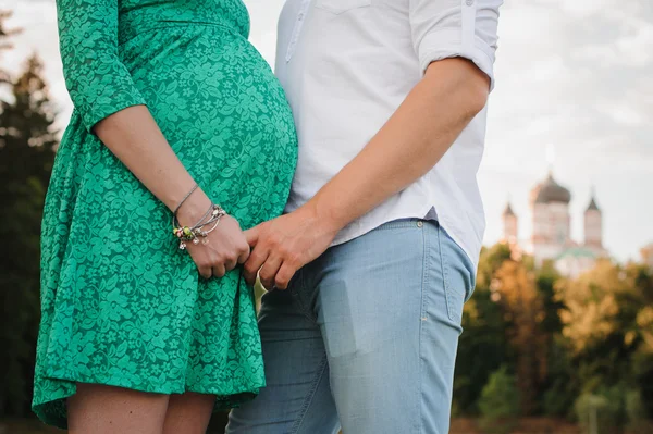 Kobiety w ciąży i jej mąż w zielonej sukni. — Zdjęcie stockowe