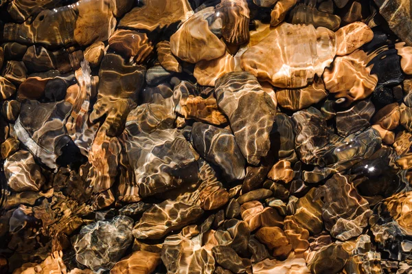 Colored pebbles under water at the coast — Stock Photo, Image