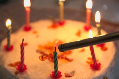 Mumlarla süslenmiş ve çakmakla aydınlatılan bir yıldönümü pastasının yakın çekimi.