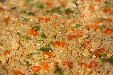 Çin pilavı stili pilav ile pişirilmiş tabağın resmi. Yeşil biber, havuç, bezelye, yumurta ve etle birlikte üç lezzetli.