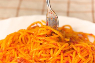 Etli ve domatesli spagetti bolonezinin üzerindeki çatalın yakın çekimi.