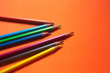 Turuncu bir yüzeyde ve fotokopi alanında bir grup dağınık renkli boya.