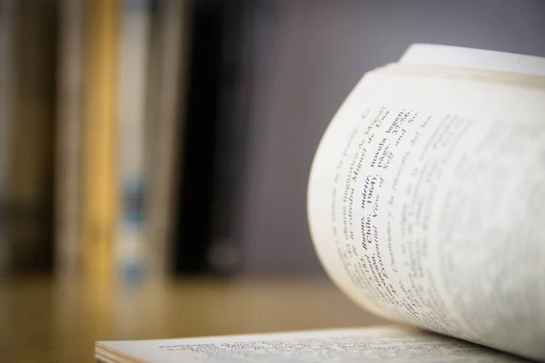 Close-up of the printed pages of a reading book open to any page, in the background some other unfocused books, with copy space