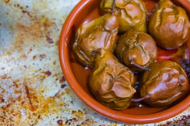 Metal bir tabakta derisi olan kavrulmuş armutlar içeren fırın güvecinin üst görüntüsü