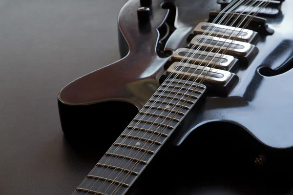 Černá elektrická kytara ležící na stole — Stock fotografie