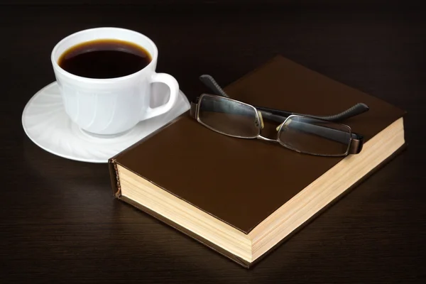 Коричневая книга с очками на столе — стоковое фото