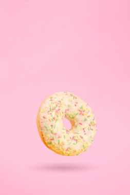 Pembe arka planda donut, havada gölgeler var.