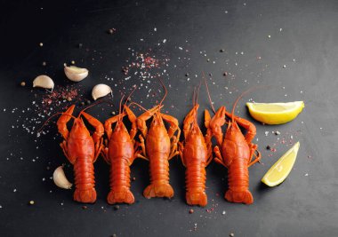 Sarımsaklı limonlu ıstakoz ve siyah arka planda kuru biber.