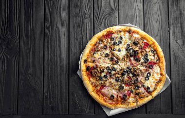 Koyu siyah tahta üzerinde geleneksel İtalyan pizzası, üst görünüm, metin için yer