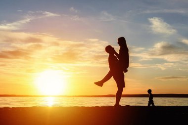 Çift kumsalda mutlu gün batımı romantik öpücük silueti