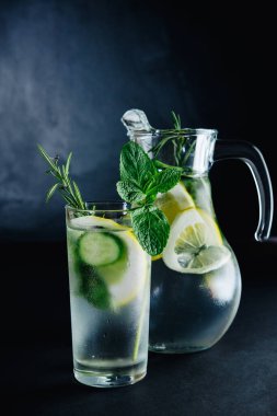 Taze yaz içeceği. Sağlıklı cam detoks köpüklü su, limon, nane, biberiye ve salatalık koyu arkaplanda. Sağlıklı gıda konsepti. Detoks diyeti.