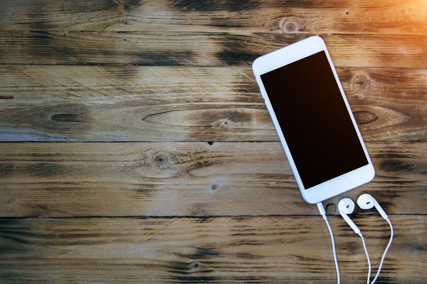 Smartphone et écouteurs sur fond en bois. Ton rétro — Photo