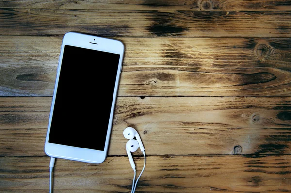 Smartphone et écouteurs sur fond en bois. Ton rétro — Photo