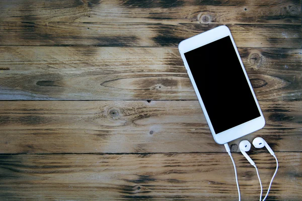 Smartphone et écouteurs sur fond en bois. Ton rétro — Photo