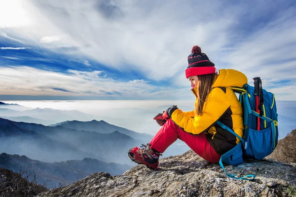 Mladá žena sedí na kopci vysokých hor. — Stock fotografie