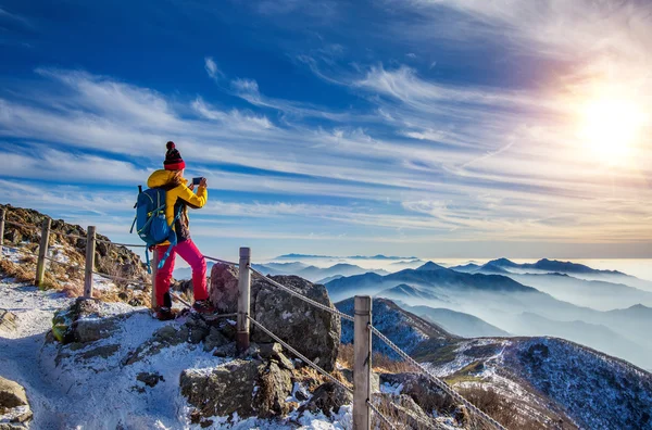 Mladá žena tramp brát fotografie s smartphone na vrchol hory. — Stock fotografie