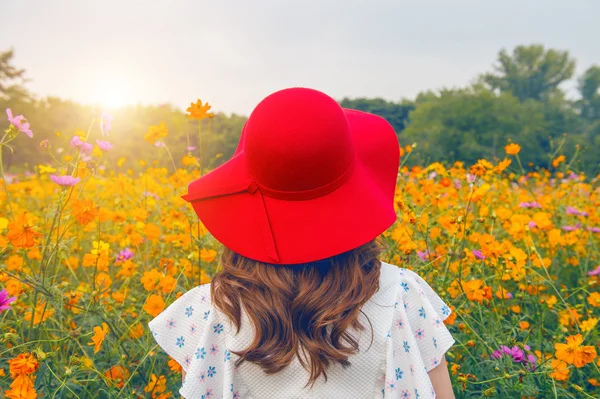Frau mit rotem Hut in einem Blumenfeld. — Stockfoto