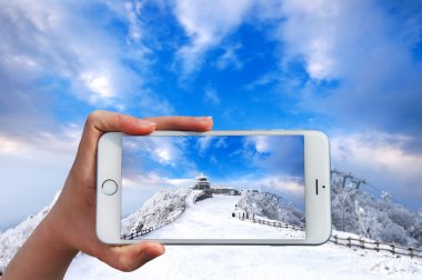 Akıllı telefon almak bir fotoğraf Deogyusan dağlar kış aylarında tutan el.