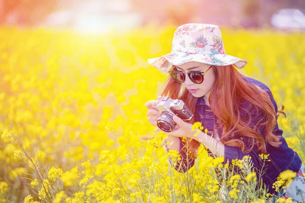 Woman taking photos at a rapeseed flowers. — Stock Photo, Image