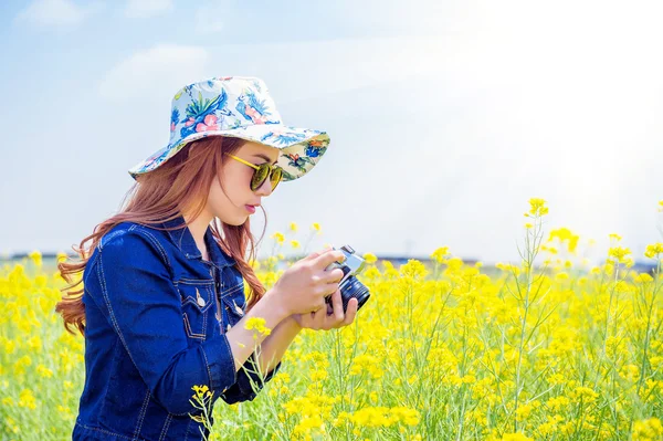 Vrouw nemen van foto's op een koolzaad bloemen. — Stockfoto