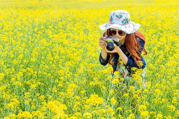 Woman taking photos at a rapeseed flowers. — Stock Photo, Image
