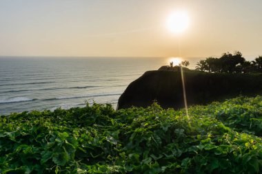Lima Peru sahilinde gün batımı manzarası, çimenli ve ağaçlı bir parktan manzara