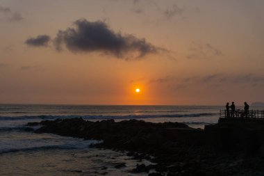 Lima Peru sahilinde gün batımı manzarası, kaya yığını.