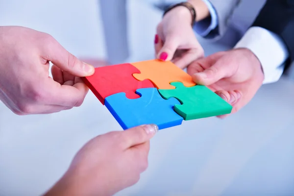 Business people assembling jigsaw — Stock Photo, Image