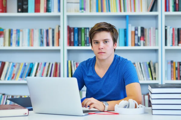 Männlicher Student, der in einer Bibliothek arbeitet — Stockfoto