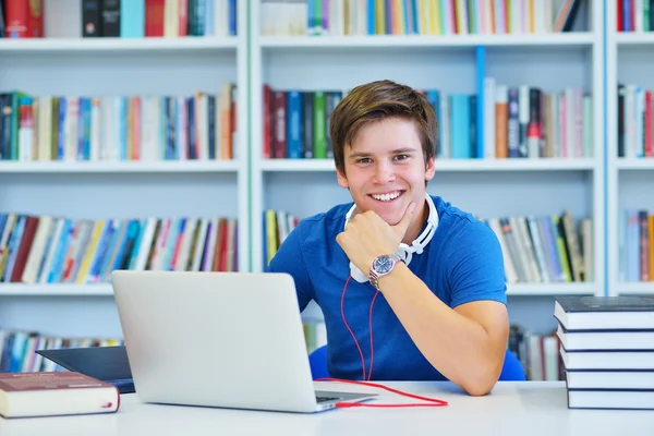 Männlicher Student, der in einer Bibliothek arbeitet — Stockfoto