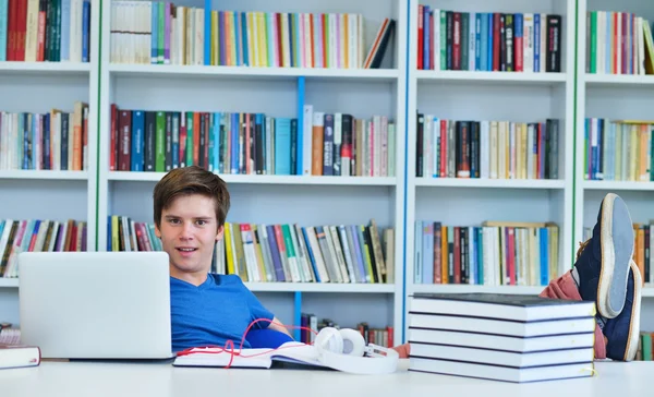 Männlicher Student, der in einer Bibliothek arbeitet — Stockfoto