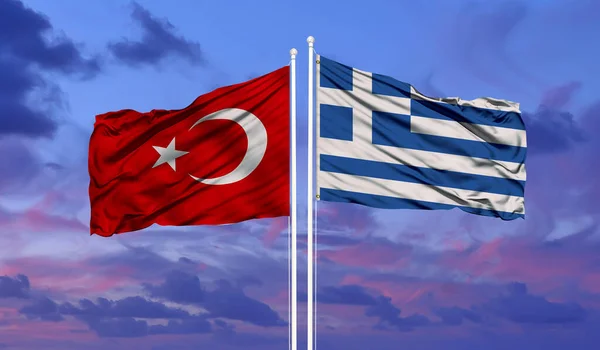 Greece and Turkey neighbor countries relations concept. Turkish and Greek flags waving against blue sky with clouds background. 3d illustration