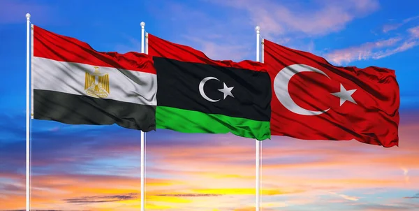 The flags of Egypt, Turkey, and Libya flutter in the sky, the concept of conflict in the Libyan state