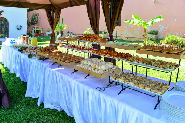 dessert buffet line on white tables in the garde