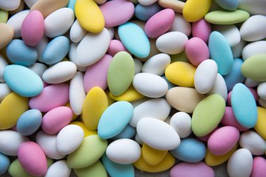 Background of sugared almonds color blue, rose, green, yellow, beige and white. clipart