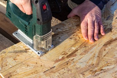 Bir işçi yapbozla bir OSB kağıdını kesiyor.