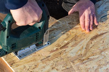 Bir işçi yapbozla bir OSB kağıdını kesiyor.