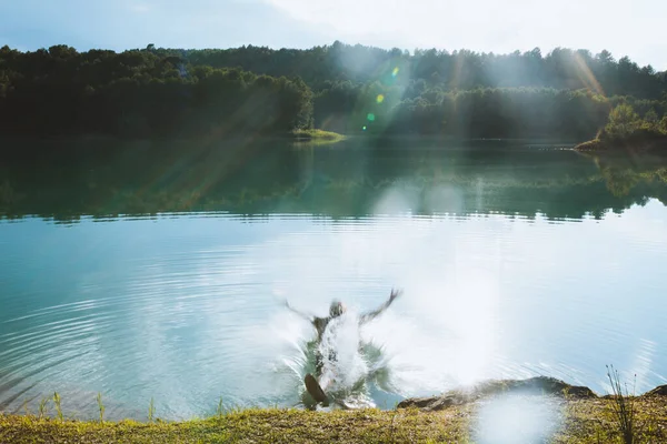 Men falling in lake on sunny day