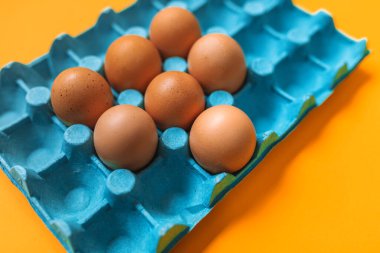 Closeup view of eggbox with eggs on orange background clipart