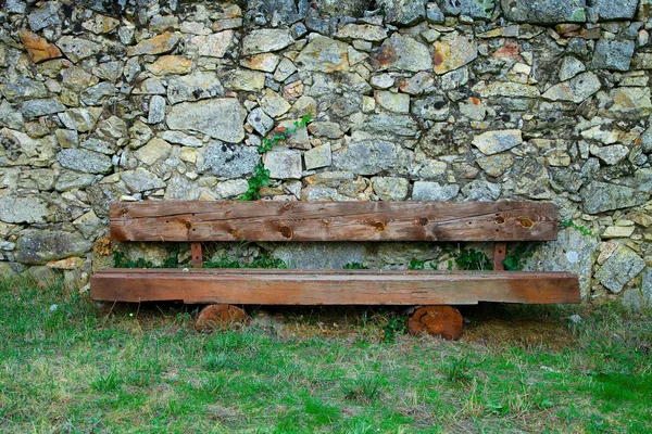 Banco de madera frente a una pared de roca — Foto de Stock