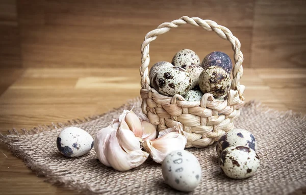 Bird eggs in wicker basket on wooden background