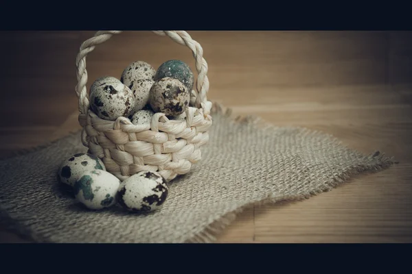 Quail eggs in a basket on a wooden background — Stock Photo, Image