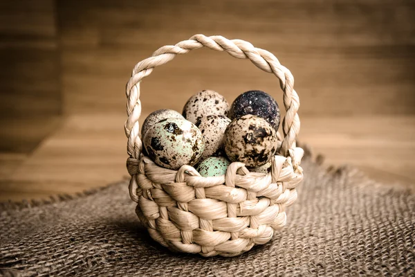 Quail eggs in a basket on a wooden background — Stock Photo, Image