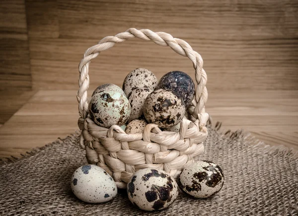 Quail eggs in a basket on a wooden background — Stock Photo, Image