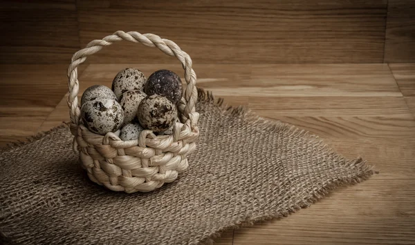 Tahta bir arka planda sepetteki bıldırcın yumurtaları.
